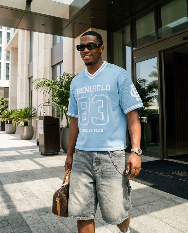 Benir Clothing light blue knit jersey with number 83 graphic, worn by a man in sunglasses and denim shorts.